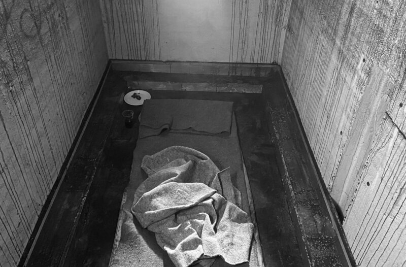Nachgestellte Zelle, in der die Inhaftierten mit „weißer Folter“ traktiert werden: ein kleiner fensterloser Raum, hell und Tag/​Nacht mit künstlichem Licht erleuchtet. – Bild: HR