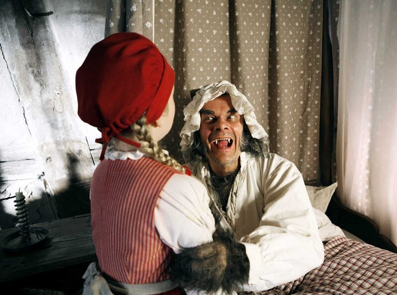 Der böse Wolf (Edgar Selge) hat sich als Rotkäppchens Großmutter verkleidet und versucht, Rorkäppchen (Amona Aßmann) zu verschlingen. – Bild: HR/​Felix Holland
