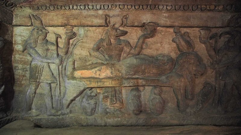 Wandschnitzerei von Anubis, der jemanden mumifiziert, Kom el Shoqafa. (Windfall Films) – Bild: Windfall Films /​ Windfall Films