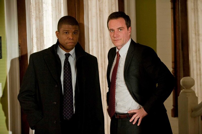 Peter (Tim DeKay, re.) bittet Agent Jones (Sharif Atkins), Neals undurchsichtigen Freund Mozzie im Auge zu behalten. – Bild: Warner TV Serie