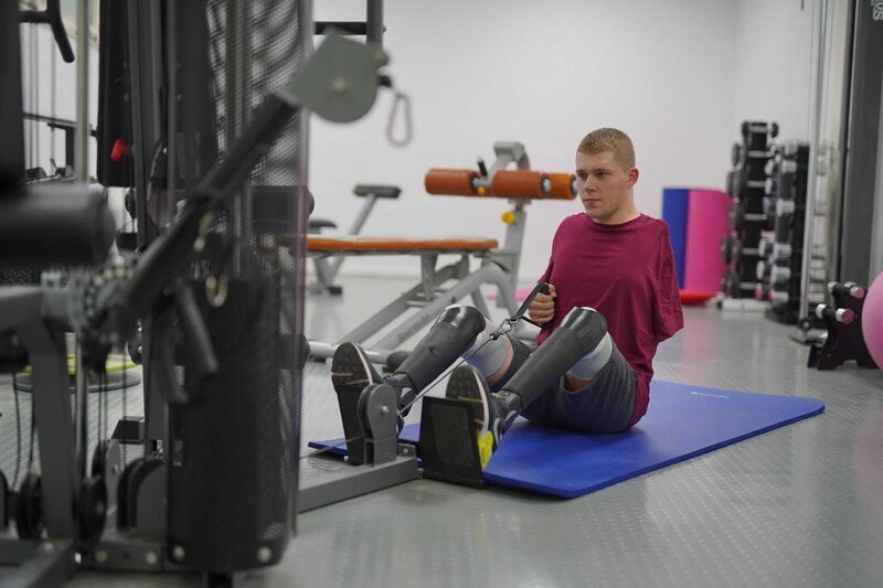 Niklas ist im Trainingsraum und sitzt an einem Gerät, welches die Armmuskulatur trainiert. Er trainiert sehr fokussiert. – Bild: ZDF und Sophie Gornostaj./​Sophie Gornostaj