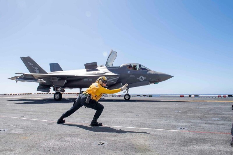 PACIFIC OCEAN (Sept. 30, 2019) Aviation Boatswain’s Mate (Handling) 2nd Class Sabrina Bales, assigned to the amphibious assault ship USS America (LHA 6, signals an F-35B Lightning II assigned to the Flying Leathernecks of Marine Fighter Squadron (VMFA) 122 to take off from the ship’s flight deck. America is currently underway conducting routine operations. – Bild: Petty Officer 3rd Class Vance Ha /​ U.S. Navy /​ Digital /​ Public Domain