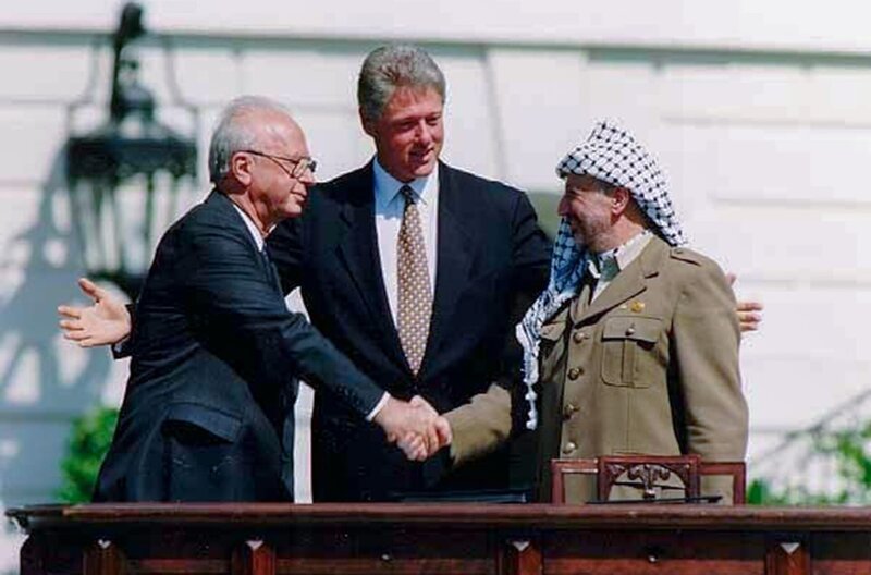 Oslo-Abkommen 1993: Händedruck zwischen dem israelischen Ministerpräsidenten Jitzchack Rabin (li.) und dem Palästinenserführer Jassir Arafat (re.) unter Aufsicht von Bill Clinton (Mi.) – Bild: Nara /​ Oslo-Abkommen 1993: Händedruck zwischen dem israelischen Ministerpräsidenten Jitzchack Rabin (li.) und dem Palästinenserführer Jassir Arafat (re.) unter Aufsicht von Bill Clinton (Mi.)