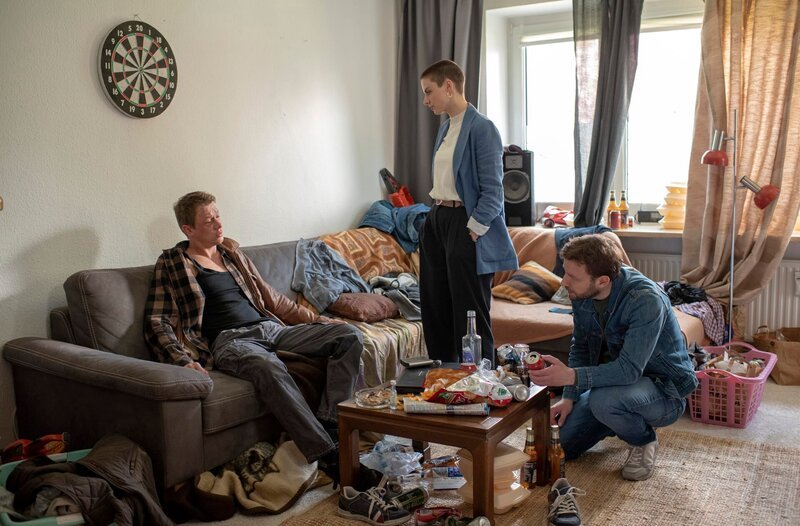 Nina (Julia E. Lenska, M.) und Gregor (Jonas Minthe, r.) überraschen Henning Mittergang (Vincent Krüger, M.) nach einer durchzechten Nacht in dessen Wohnung. – Bild: ARD/​Thorsten Jander