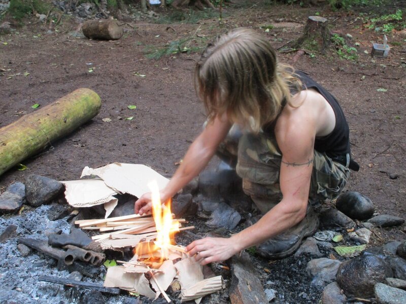 Bear Brown starting a fire with cardboard and kindling at the campsite. – Bild: Discovery Channel /​ Discovery Communications