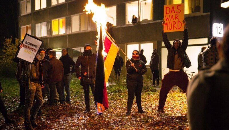 Die deutsche Flagge wird vor dem Asylbewerberheim angezündet. – Bild: NDR/​Alexander Fischerkoesen