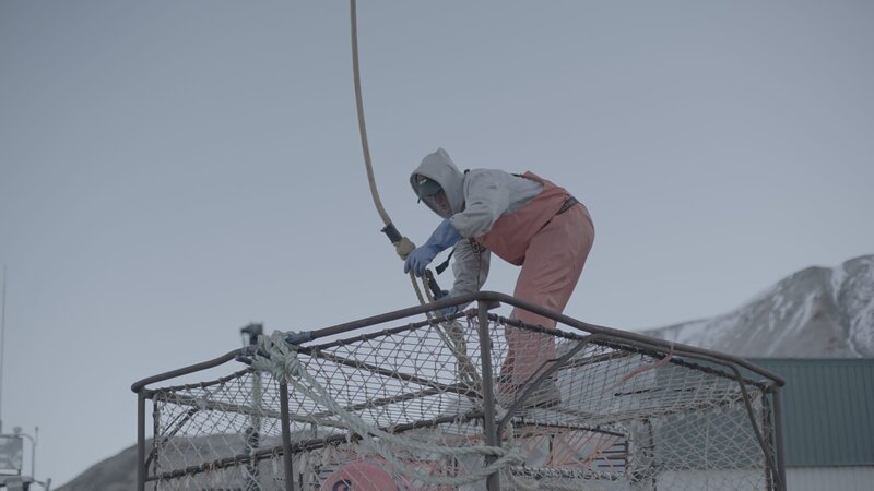 Wizard greenhorn, Caelan Colburn attaches a picking hook to a crab pot in the shipyard. – Bild: Discovery Communications