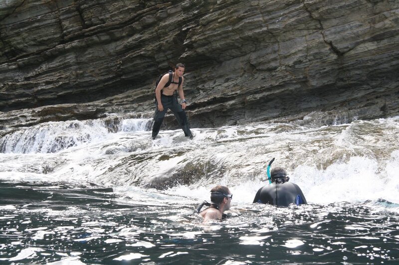Bear Grylls climbing out of the sea onto low rocks with the remnants of the wave still at his feet in Panama, Central America. – Bild: Discovery Communications
