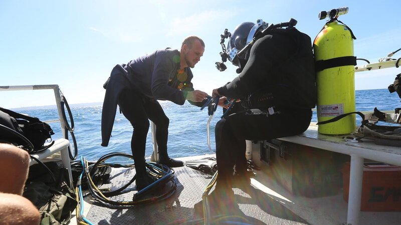 Rookie Dan helping outfit Erik in a wetsuit. – Bild: Discovery Communications