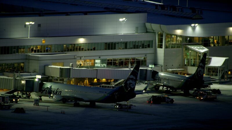 The airport terminal at night with two Alaska Airlines planes attached to passenger jetbridges – Bild: Smithsonian Channel