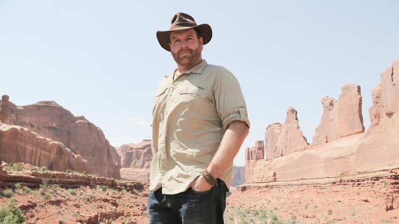 Josh Gates poses in front of stunning rock formations at Arches National Park, Utah, as seen on Travel Channel’s Expedition Unknown. – Bild: 2017, The Travel Channel, LLC. All Rights Reserved.