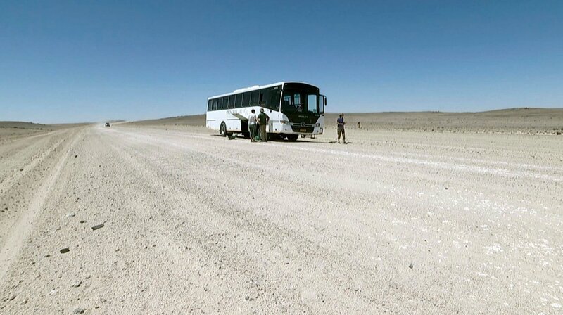 Auf der Strecke quer durch die Wüste nach Swakopmund werden die Reisenden durch eine Buspanne aufgehalten. – Bild: HR