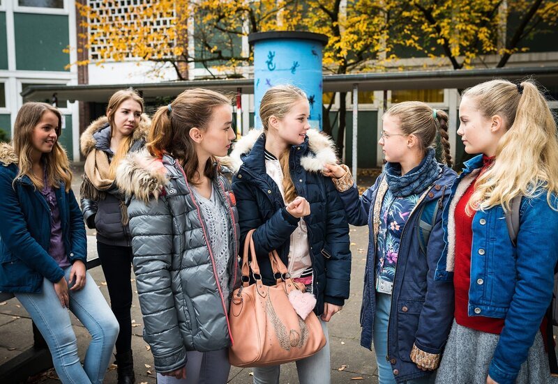 Angewidert begutachtet Pinja (Sina Michel, 2. v. r.) die neue Echtfelljacke ihrer Mitschülerin Joelle (Liva Stege). – Bild: NDR/​Boris Laewen