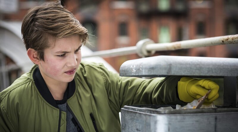 Johannes (Luke Matt Röntgen) durchsucht fieberhaft die Mülleimer in der Umgebung des Cafés nach Indizien. – Bild: NDR/​Boris Laewen