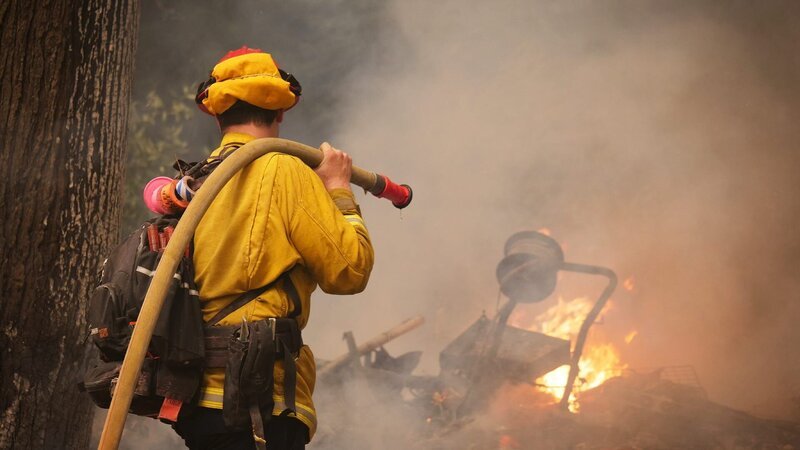 Feuerwehrmann bei der Verlegung von Schläuchen an der Front des Glass Fire außerhalb von Angwin in Napa County, Kalifornien. – Bild: Warner Bros. Discovery
