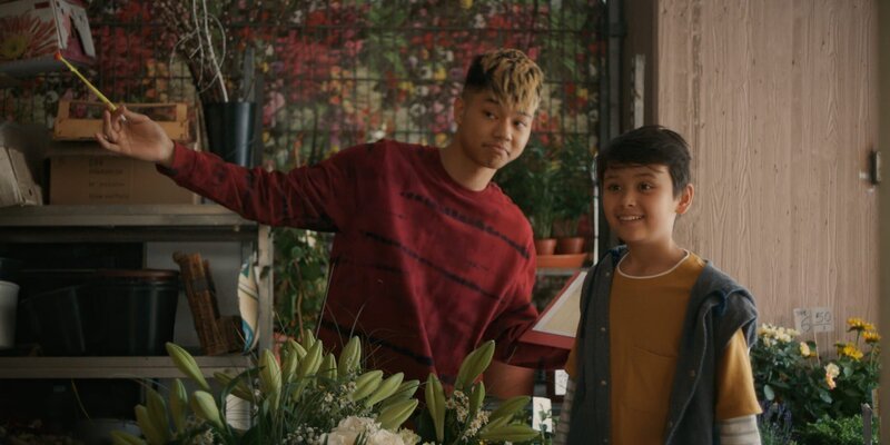 Noah (Hauke Tài Hoàng) und sein Bruder Liam (Quang Anh Lê) helfen den Eltern in ihrem Blumenladen. Sie beobachten, wie sich ihr Vater überschwänglich bei seiner Frau entschuldigt und finden das peinlich. – Bild: ZDF/​StudioZentral