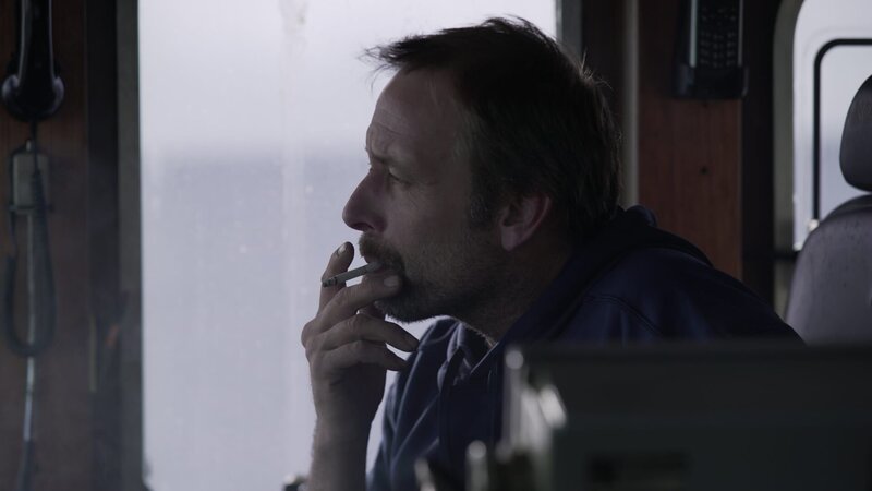 Edgar smokes a cig while relieving Captain Sig in the wheelhouse. – Bild: Discovery Channel /​ Discovery Communications