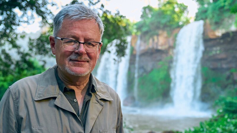 Moderator Christopher Clark erklärt die Besonderheiten des von der Unesco geschützten Regenwaldes bei den Wasserfällen von Iguazú. – Bild: ZDF und Sebastian Richteer./​Sebastian Richteer
