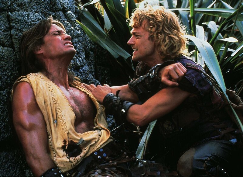 Iolaus (Michael Hurst, re.) hilft seinem schwerverletzten Freund Hercules (Kevin Sorbo). Er wurde von dem Pfeil einer Kriegerin getroffen. – Bild: RTL