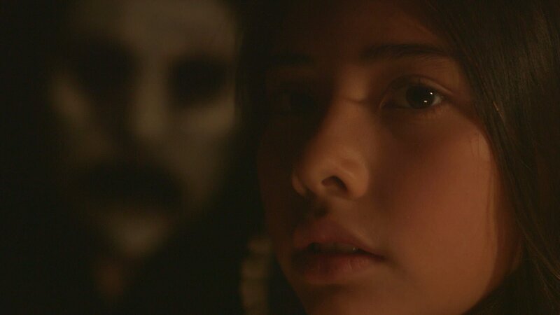 Young Adriana looks around as the ominous mask lurks in the background. – Bild: Destination America /​ Discovery Communications