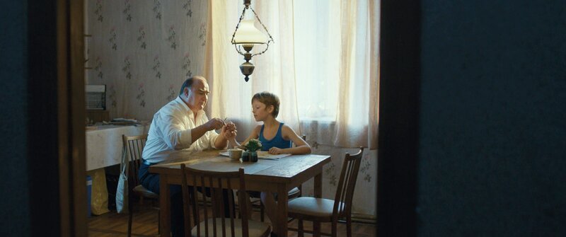 Gert (Udo Samel) schneidet Roman (Yelizar Nazarenko) in ihrem Exil in einer Waldhütte die Fingernägel. – Bild: ZDF und Mila Teshaieva.
