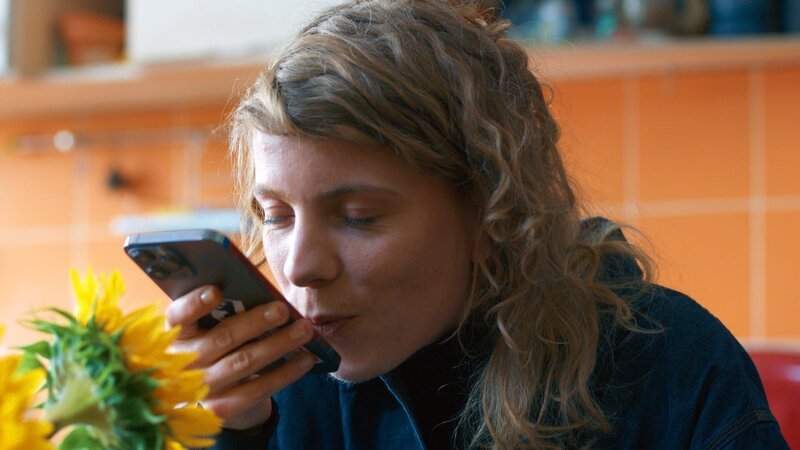 Andrea (Thea Rasche) schickt Lisa schon mal einen Kuss per Telefon und freut sich auf ihr erstes Date in Kyiv. – Bild: ZDF und Nataliia Khalan./​Nataliia Khalan