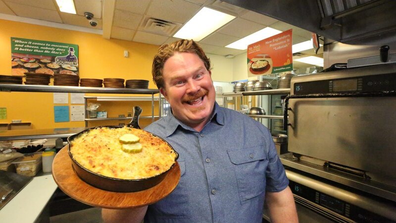 Host Casey Webb poses with the Deluxe Cheeseburger Mac at Mr. Mac’s in Manchester, New Hampshire, as seen on Man v. Food, Season 4. – Bild: Cooking Channel – US. /​ Focus. /​ Cooking Channel – US.