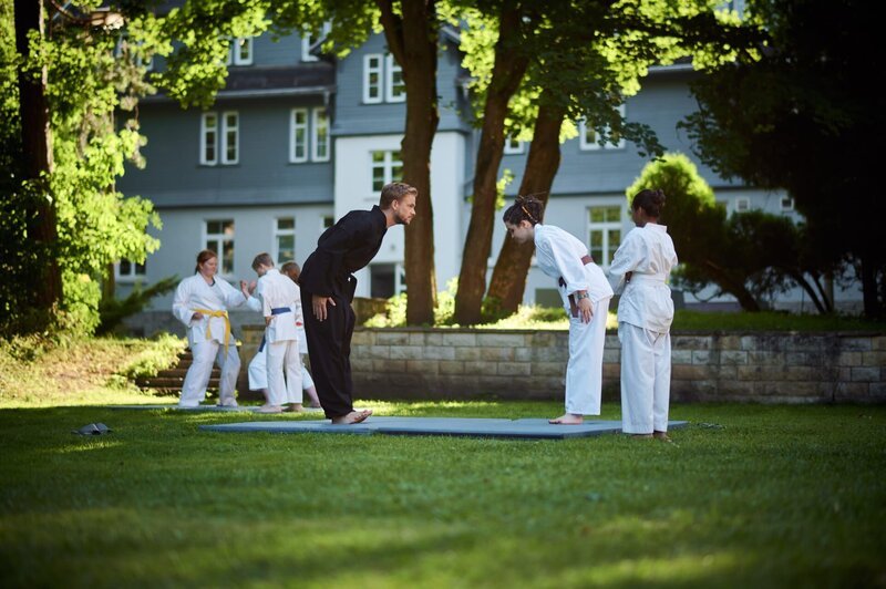Herr Hauser (Frederic Heidorn) und Sibel (Josie Hermer) geben Reena (Sophia Leonie Mauritz, r.) eine Karate-Stunde. – Bild: mdr/​Saxonia Media