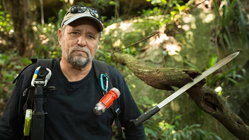 MCU – Keith Plaskett in the jungle, his machete stuck into a tree branch. – Bild: Discovery Channel