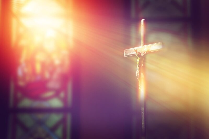 Jesus on the cross in church with ray of light from stained glass. – Bild: Shutterstock