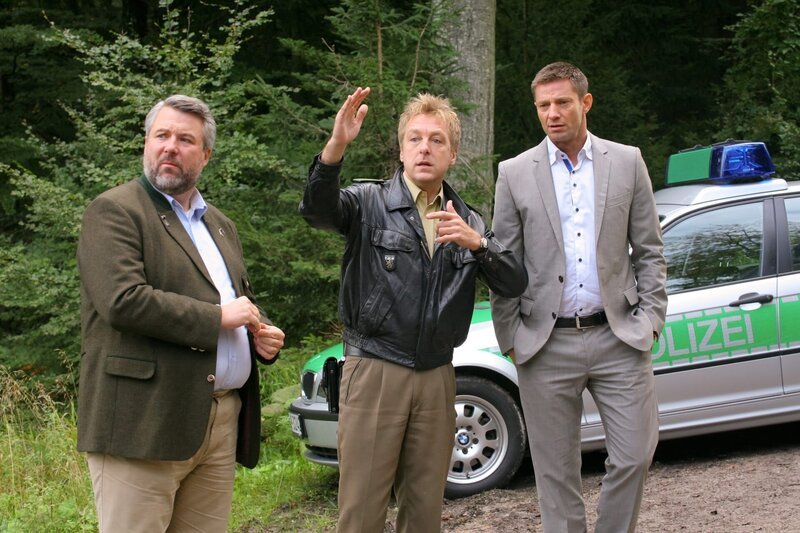 Als ein Forstbesitzer morgens tot in seinem Wald gefunden wird, ermitteln die Rosenheimer Kommissare Stadler (Dieter Fischer, l.), Hansen (Igor Jeftic, r.) und Polizist Mohr (Max Müller, M.). – Bild: ZDF /​ Christian A. Rieger
