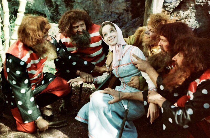 Mit einer prächtigen Troika aus weißen Schimmeln schafft es der Abgesandte des bösen Zauberers Kastschej die schöne Aljonuschka (Natalja Sedych, Mitte) zu rauben. Nachdem Kastschej Aljonuschka seine silber-goldenen Bäume gezeigt hat, versucht diese mit ihrer Ziege Weißchen zu fliehen. Weißchen entkommt, aber Aljonuschka wird von den Wächtern (Dritter v.r.:  A. Kubatskiy) des bösen Zauberers festgehalten. – Bild: MDR/​Progress