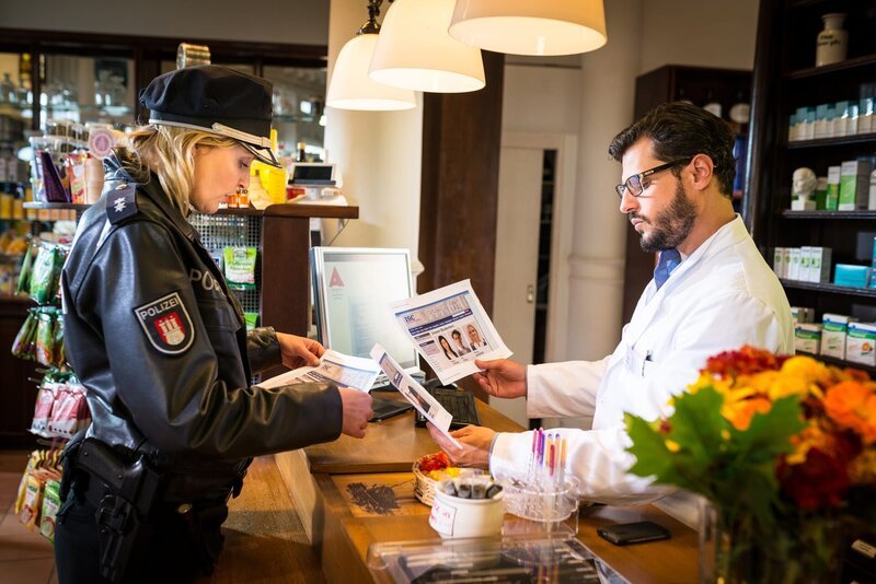 Melanie (Sanna Englund) zeigt dem Apotheker (Manuel Cortez) Fotos der Studenten und lässt sich bestätigen, wer bei ihm leistungssteigernde Drogen auf Rezept eingelöst hat. – Bild: ZDF und Boris Laewen./​Boris Laewen