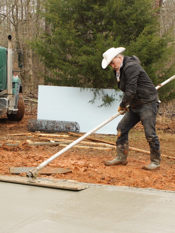 Marty is smoothing out concrete with a large tool that resembles a mop. – Bild: Scott Sandman /​ Photobank. /​ Discovery Communications, LLC