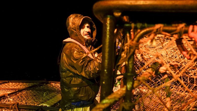Deckhand Nick Mavar, secures pots on the stack with ties at night. – Bild: Nate Chambers /​ Discovery Channel /​ Discovery Communications, LLC