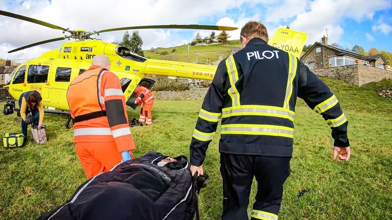Rettungssanitäter und ein Pilot tragen einen verletzten Mann – Bild: Warner Bros. Discovery