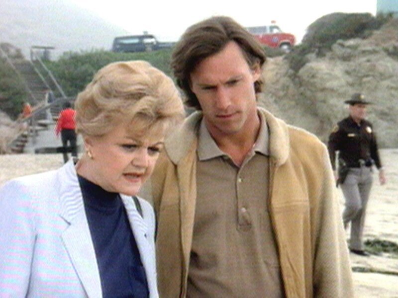 Jessica Fletcher (Angela Lansbury) und Pater Barns (Hunt Block) entdecken die Leiche des stadtbekannten Weiberhelden Evan West am Strand von Cabot Cove. – Bild: Warner TV Serie