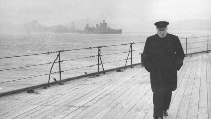 Das Foto zeigt Premierminister Winston Churchill in voller Länge auf dem Deck der H.M.S. Prince of Wales während der Atlantikkonferenz. – Bild: RTL/​ (c) Public Domain -U.S. Office of War Information