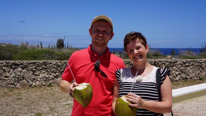 Passagiere Isabell und Bastian trinken ihre erste Kokosnuss an der Alto Vista Chapel auf Aruba in der Karibik – Bild: BR/​Deborah Stöckle