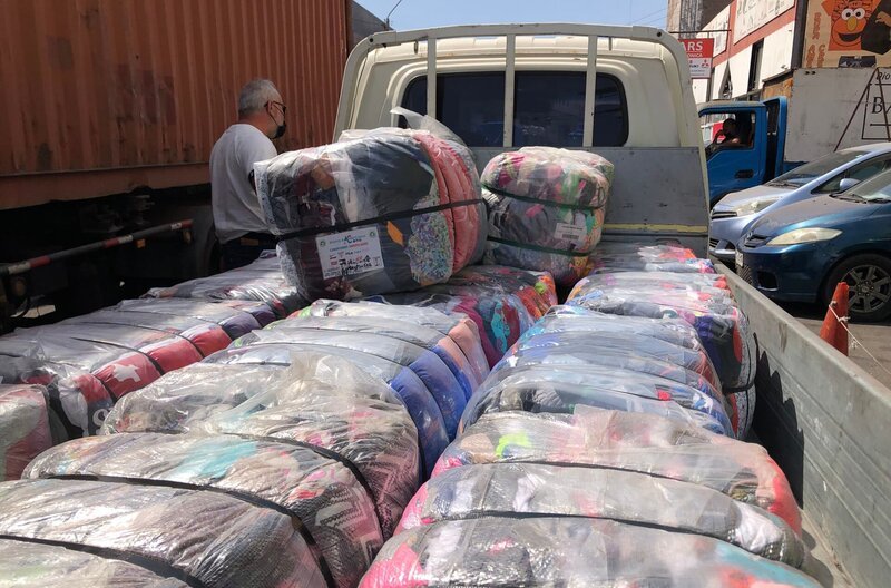 In der Freihandelszone „Zofri“ in Iquique kommen die Altkleider in Ballen verpackt mit dem Container aus Europa an. Was die Händler nicht gebrauchen können, werfen sie in die Wüste. – Bild: NDR/​SWR