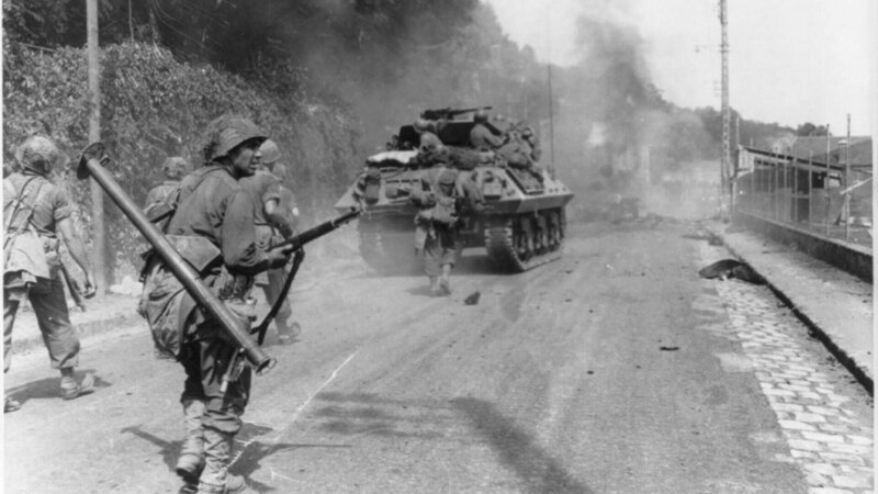 Amerikanische Truppen bewegen sich auf dem Weg nach Paris in Richtung Fontainebleau, während der Rauch von gesprengten deutschen Panzern den Himmel erfüllt. – Bild: RTL/​ (c) Public Domain – U.S. Library of Congress