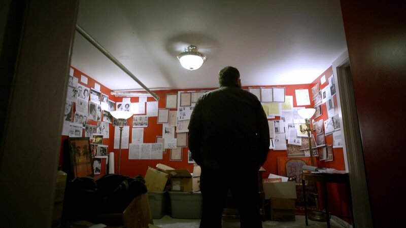 Ein Mann steht in einem Raum und schaut auf die Wände, an denen die Details des Falles hervorgehoben sind – Bild: viacom /​ © Crime + Investigation /​ Viacom