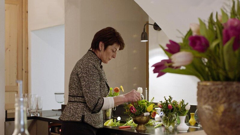 Eine Frau arrangiert Blumensträuße. – Bild: Bergblick