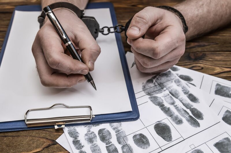 Men’s hands with handcuffs fill the police record, confession. – Bild: Shutterstock /​ Shutterstock /​ Copyright (c) 2018 Shutterstock. No use without permission.