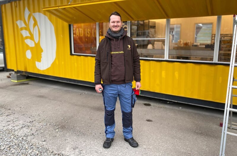 Erfinder Simon Zimmermann steht vor dem Prototyp seiner Solarbakery auf dem Impact Hub Gelände in Stuttgart. Ein rund 14 Meter langer Container wurde in eine Bäckerei umgewandelt. – Bild: MDR/​Nathalie Pfeiffer