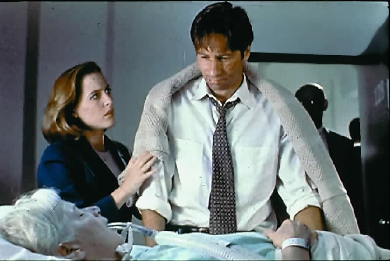 Mrs. Mulder (Rebecca Toolan, vorne) wurde mit einem Schlaganfall in ein Krankenhaus eingeliefert. Scully (Gillian Anderson, l.) steht Mulder (David Duchovny, r.) bei, der das Leben seiner Mutter mit den Kräften eines Außerirdischen retten möchte. – Bild: SYFY