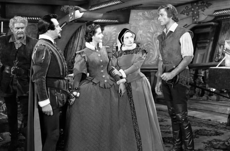 Der Herr der sieben Meere – Bild: Warner Bros. /​ Kapitän Thorpe (Errol Flynn, re.) und seine Mannschaft plündern eine spanische Galeasse. Es ist das Schiff des Botschafters Don José (Claude Rains, 2.v.l.), der seine Nichte Doña Maria (Brenda Marshall, Mi.) an den  …