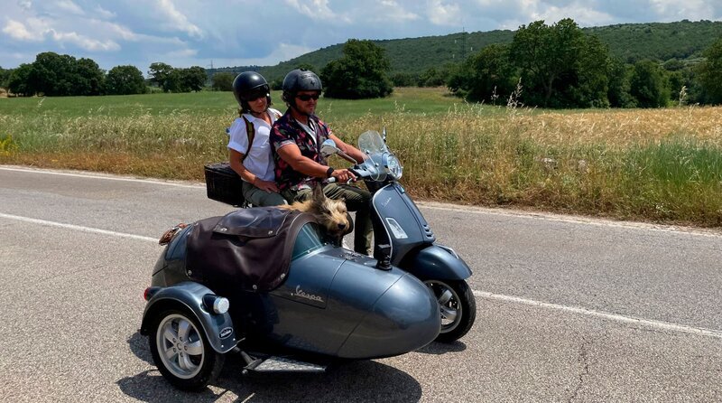 Andreas (63, r.) und Britta (58) mit Hund Toni. Sie machen ihre allererste Spritztour mit der neuen Vespa in Italien. – Bild: WDR/​Liliane Mofti/​Sagamedia