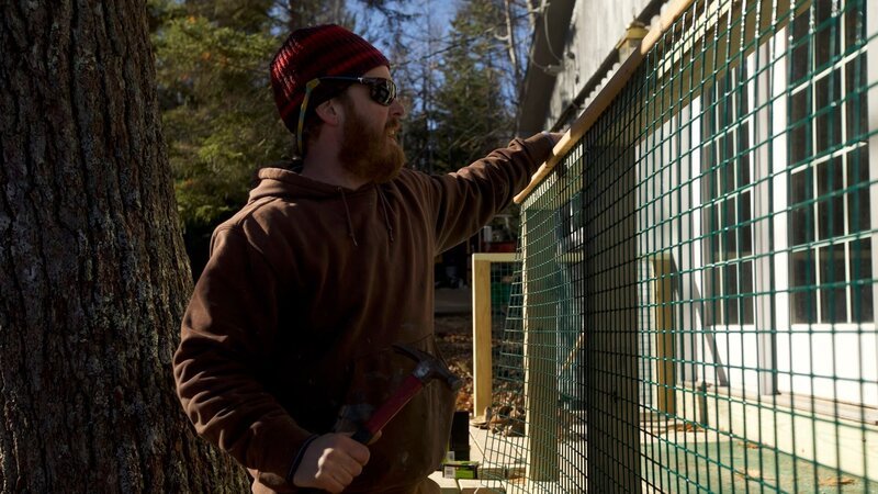 Builder, Chase is attaching lobster trap metal to the deck as railing, it’s sturdy and can handle any type of weather, for Kirk and Lisa’s cabin build, in Lincolnville, Maine, as seen on DIY Network’s Maine Cabin Masters. – Bild: 2018, Scripps Networks, LLC. All Rights Reserved.