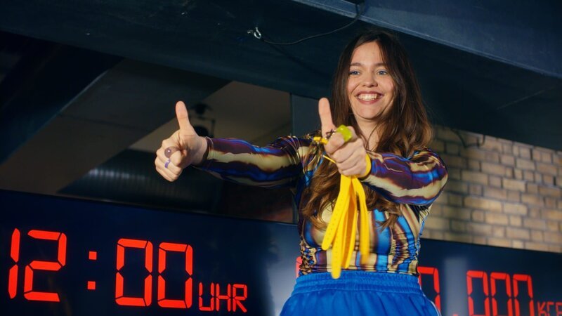 Thumbs up! Mia (Lotte Becker) motiviert die Leute für den Fitnessmarathon. – Bild: ZDF und Daniel Leibold./​Daniel Leibold